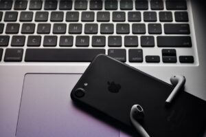 Laptop with a smartphone and AirPods 2nd Generation on a desk.