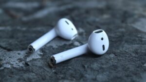 Two individual AirPods 3rd Generation earbuds lying apart on a textured grey stone surface.