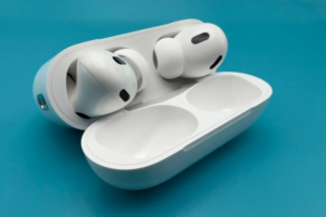 AirPods Pro earbuds placed next to their open charging case on a blue background, highlighting the design and features of the latest model.