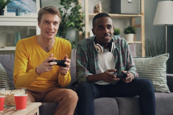 two men sitting on a couch playing video games