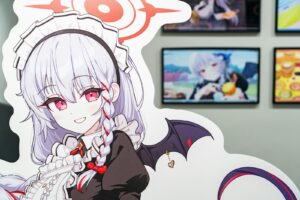 A woman with white hair and red eyes is standing in front of a wall with