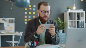 Man playing game on smartphone at office desk