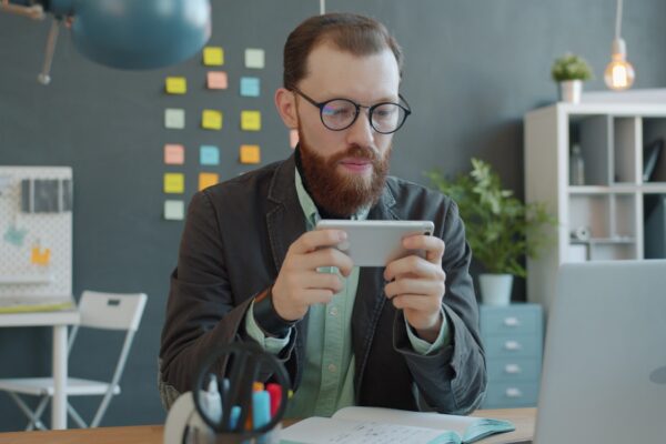 Man playing game on smartphone at office desk