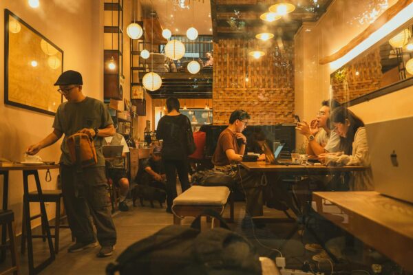 Warm and inviting coffee shop interior with people working and socializing, evening ambiance.