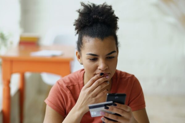 Woman looking at phone with credit card in hand