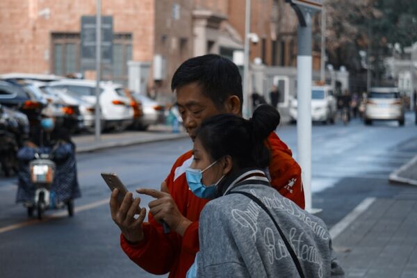 man in gray sweater carrying child in red jacket