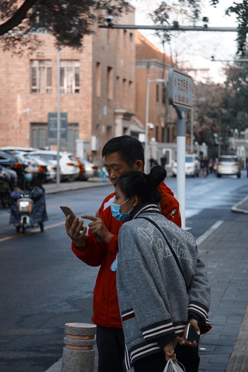 man in gray sweater carrying child in red jacket