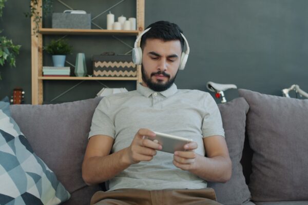 Man wearing headphones plays game on phone