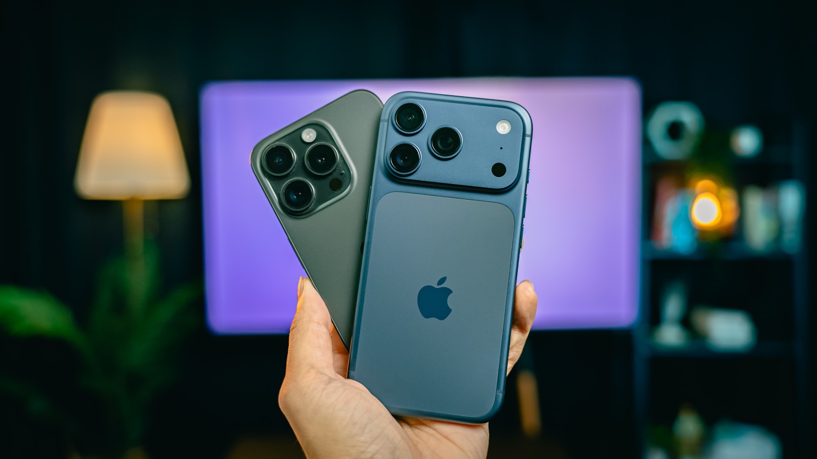 Two iphones held in a hand, blurred background.