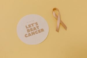 Flatlay of a cancer awareness ribbon and motivational message, promoting cancer support.