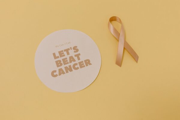 Flatlay of a cancer awareness ribbon and motivational message, promoting cancer support.