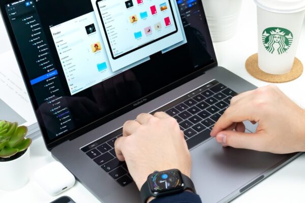 person using laptop between Starbucks cup and iPhone