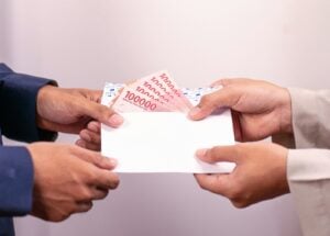 A person is giving money in an envelope